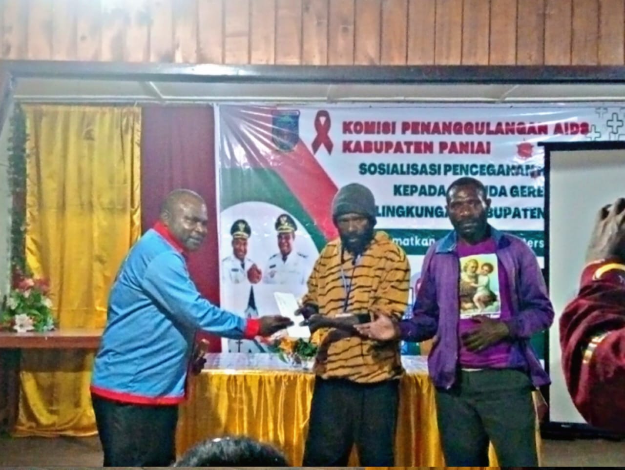 Ketua KPA Paniai Sepanya Yogi baju biru (kiri) serahkan sumbangan suka rela kepada ketua panitia pelaksana, bagian (kanan), Rabu (26/11/2025).